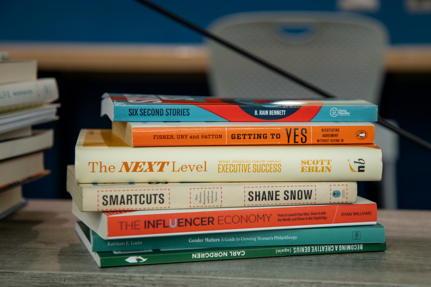 Stack of business and self-help books on a light wood table.
